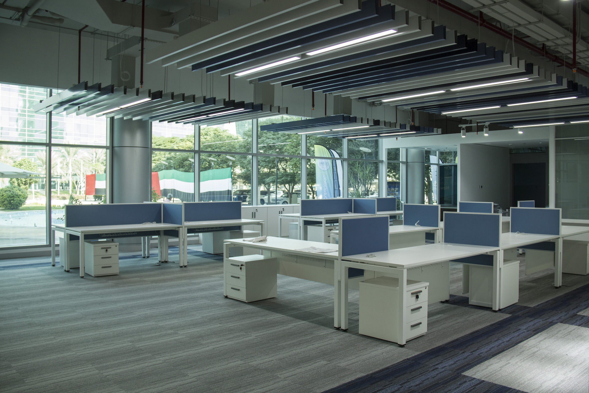Interiors of Jafza 17 office. There are white desks in a room with a big stained glass wall