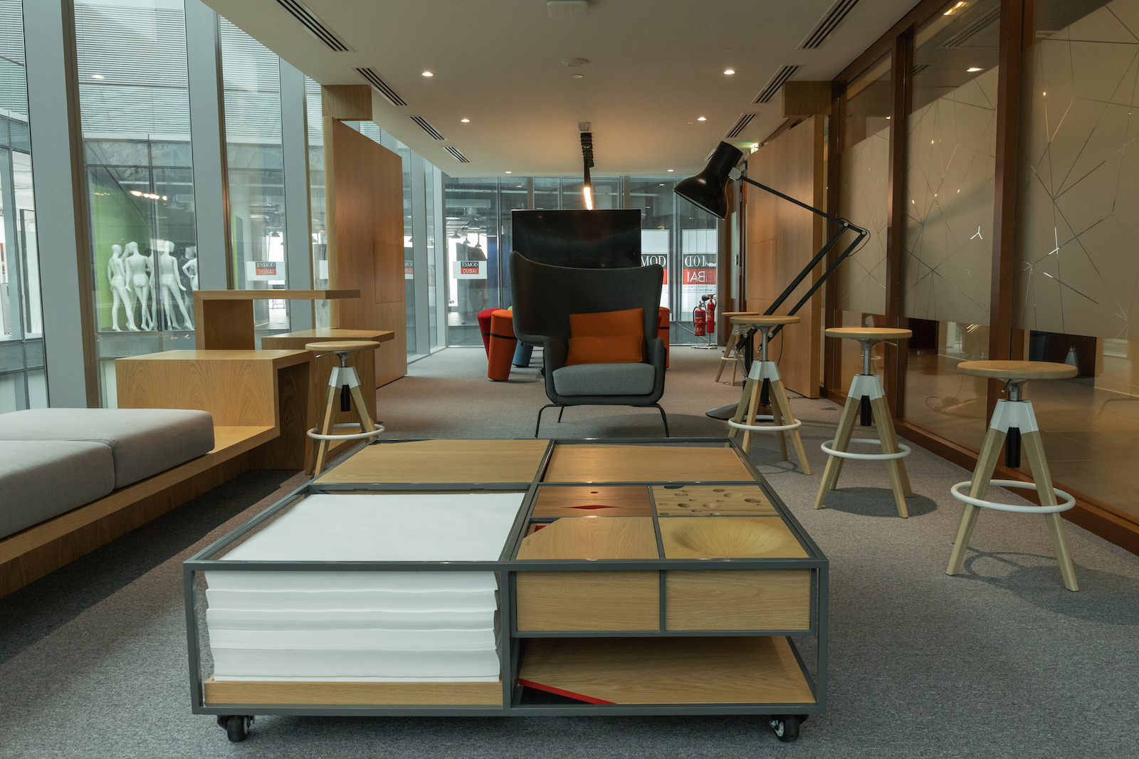 Tecom meeting room interiors. There are a large coffe table, three stools on the foreground and two armchairs in the distance