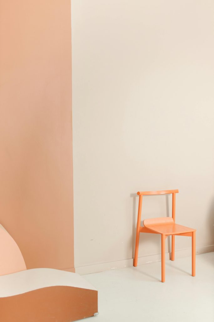Best Furniture Design Materials for Sustainable Interiors 5 Simple orange chair against a pastel wall with ample copy space, perfect for design themes.